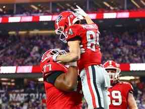 Le joueur de ligne offensive des Bulldogs de Géorgie Devin Willock (77) lève le receveur large Ladd McConkey (84) lors du match de championnat national CFP au stade SoFi.