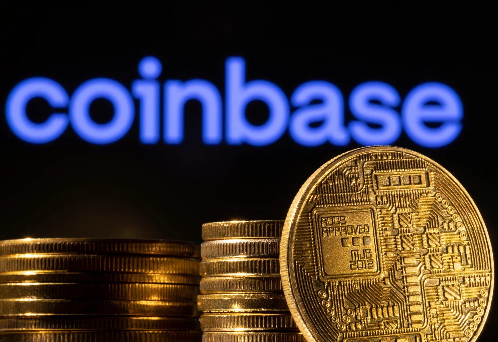 Une représentation de la crypto-monnaie est visible devant le logo Coinbase dans cette illustration prise le 4 mars 2022. REUTERS/Dado Ruvic/Illustration