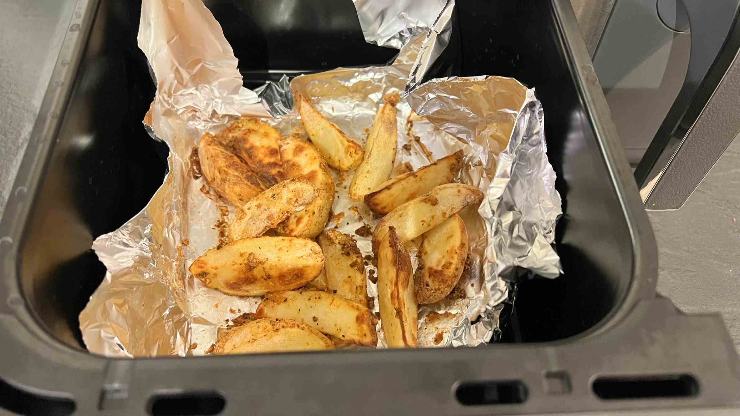 Quartiers de pommes de terre cuites dans un panier de friteuse à air