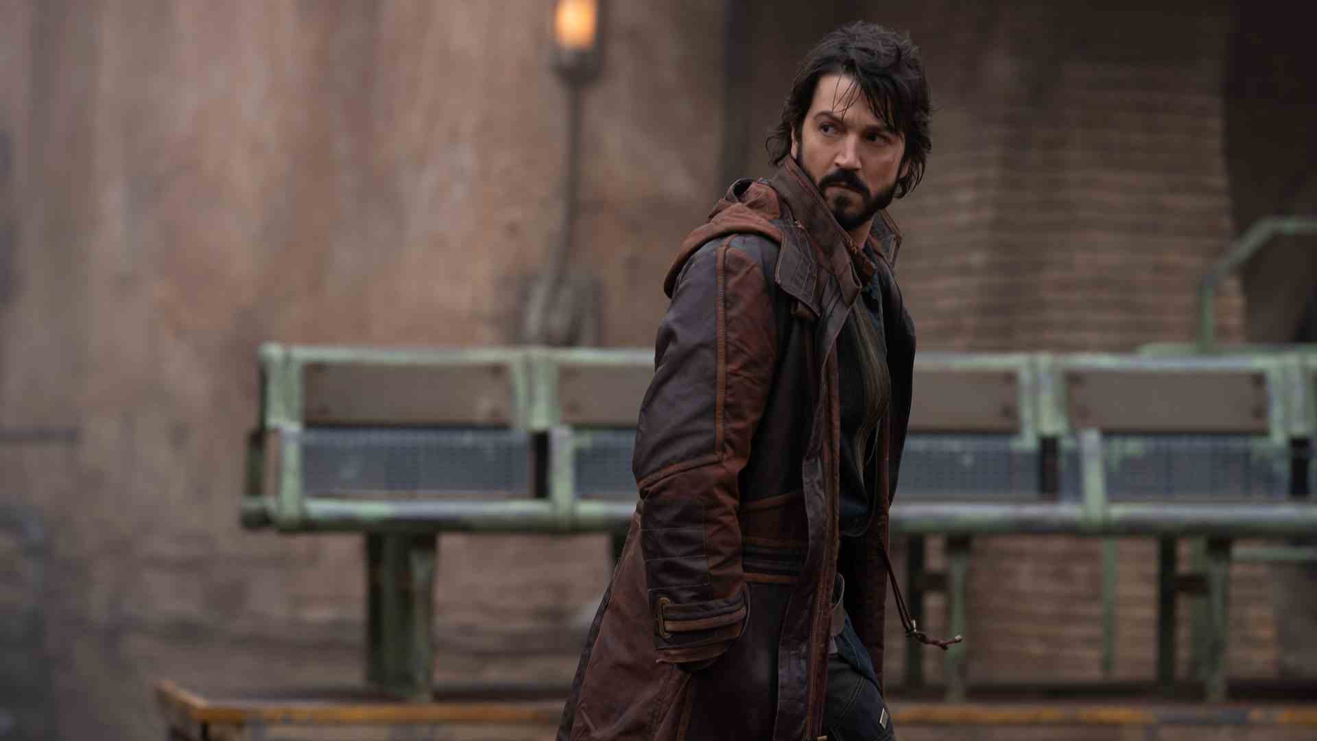 Cassian Andor regarde derrière lui alors qu'il se promène dans la ville principale de Ferrix à Andor sur Disney Plus