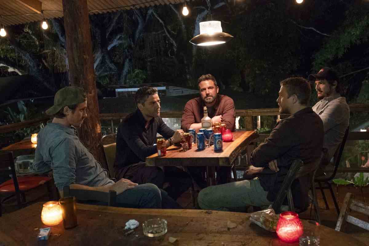 Garrett Hedlund, Ben Affleck, Oscar Isaac, Pedro Pascal et Charlie Hunnam sont assis autour d'une table avec des bières dans Triple Frontier.