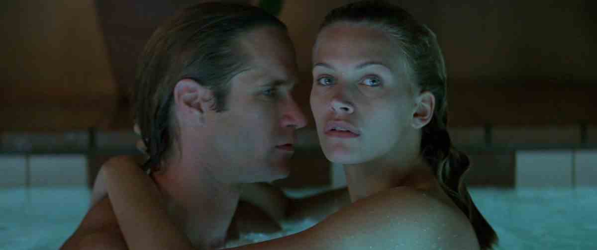 Natasha Henstridge regarde au loin tout en étreignant un homme dans une piscine dans Species