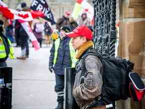 Monty Walker se tient devant les grilles d'entrée de la Colline du Parlement samedi.  Un autre membre du groupe de protestation a déclaré que Walker avait reçu un avis d'intrusion des semaines plus tôt et n'était pas autorisé sur la colline.