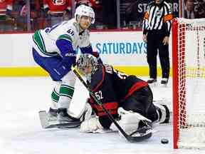 Elias Pettersson (40 ans) des Canucks de Vancouver glisse la rondelle devant le gardien des Hurricanes de la Caroline Pyotr Kochetkov (52 ans) pour remporter le match lors d'une fusillade à Raleigh, en Caroline du Nord, le dimanche 15 janvier 2023.