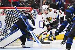 L'attaquant des Blackhawks de Chicago Cole Guttman (70 ans) tente de patiner la rondelle contre le gardien de but des Maple Leafs de Toronto Ilya Samsonov (35 ans) en première période au United Center le 19 février 2023. Jamie Sabau-USA TODAY Sports