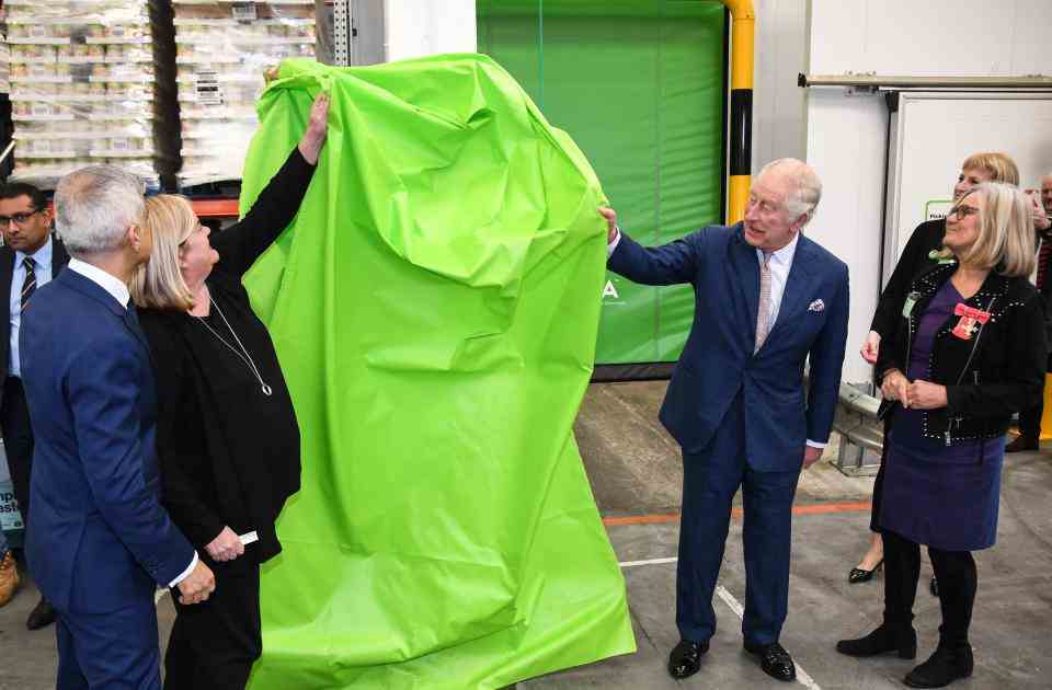 Le roi Charles III (C) de Grande-Bretagne dévoile un réfrigérateur lors de sa visite du projet Felix, une association qui fournit des repas à certaines des personnes les plus vulnérables de Londres, dans l'est de Londres, le 22 février 2023. (Photo de Jeremy Selwyn / PISCINE / AFP) (Photo by JEREMY SELWYN/POOL/AFP via Getty Images)