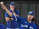 L'entraîneur des lanceurs des Blue Jays de Toronto Pete Walker, à l'arrière, regarde le lanceur partant des Blue Jays Kevin Gausman, à l'avant, lancer lors de l'entraînement printanier de baseball à Dunedin, en Floride, le dimanche 19 février 2023. 