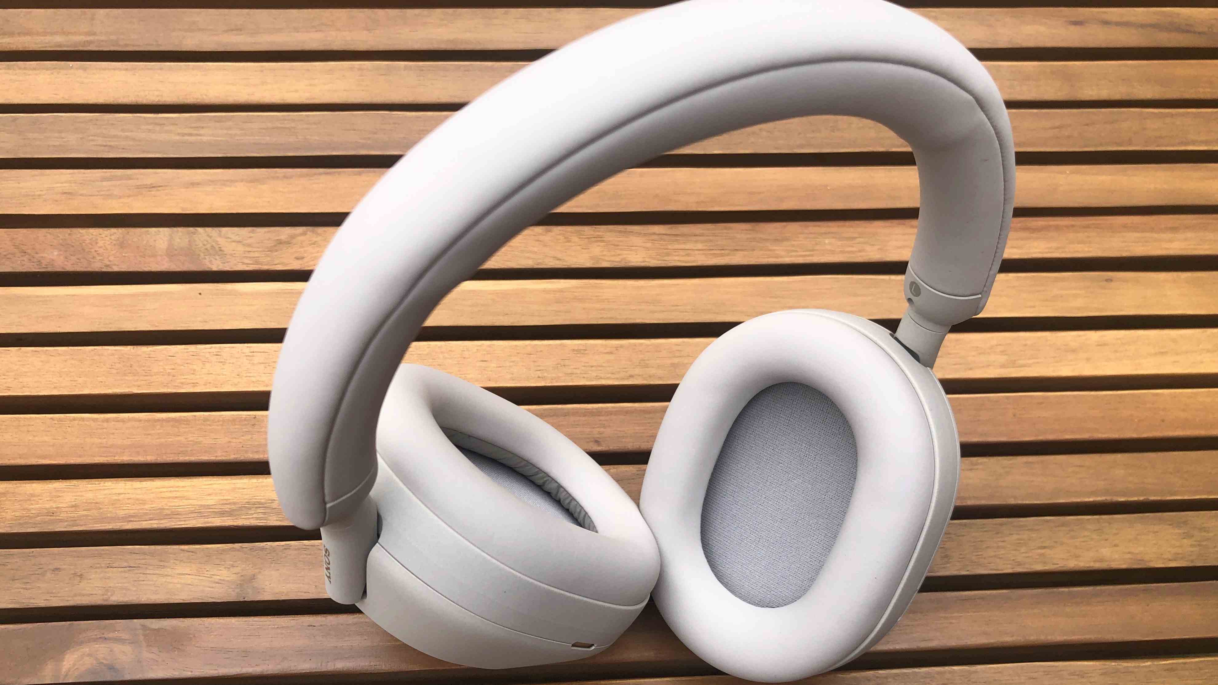 Casque Sony XM5 en écru (blanc cassé) posé en extérieur sur une table de jardin