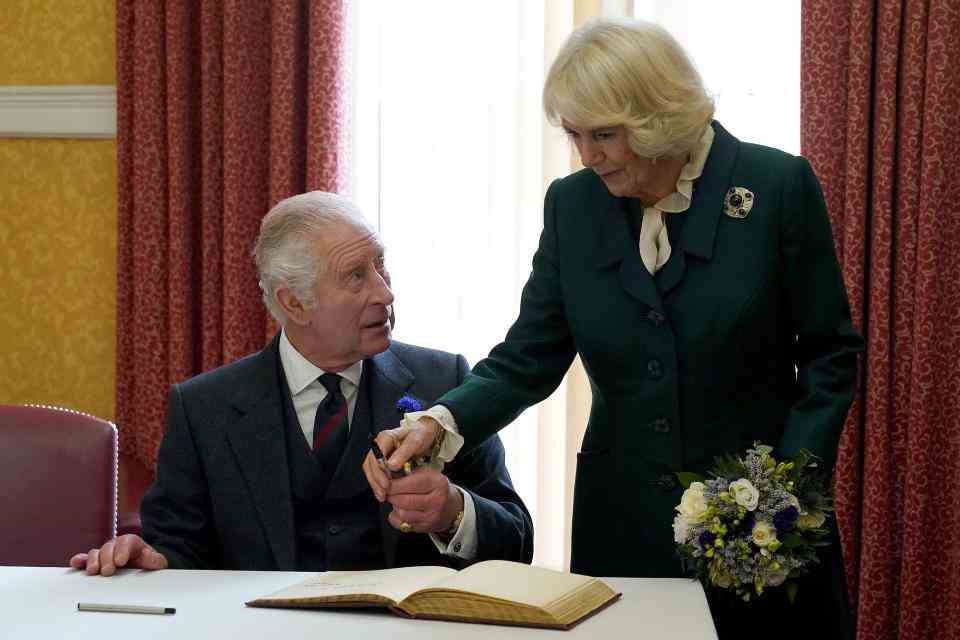 Le roi Charles III (L) de Grande-Bretagne et Camilla, reine consort de Grande-Bretagne tiennent un stylo alors qu'ils signent un visa pour les visiteurs.  bok après avoir assisté à une réunion officielle du conseil au City Chambers de Dunfermline, pour marquer officiellement l'attribution du statut de ville à l'ancienne ville, à Dunfermline, dans le sud-est de l'Écosse, le 3 octobre 2022. (Photo par Andrew Milligan / POOL / AFP) ( Photo par ANDREW MILLIGAN/POOL/AFP via Getty Images)