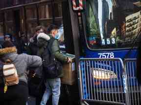 Des migrants transportent leurs affaires dans un bus après avoir accepté de déménager après avoir été expulsés de l'hôtel Watson le 30 janvier 2023 à New York.  (Photo de Michael M. Santiago/Getty Images)