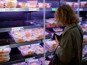 Un client regarde des emballages de morceaux de poulet réfrigérés dans une vitrine réfrigérée dans un supermarché Lidl à Walthamstow, dans l'ouest de Londres, le 21 septembre 2021.