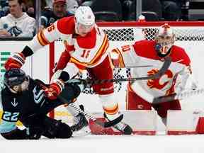 Le gardien des Flames de Calgary Dan Vladar regarde la rondelle alors que le défenseur des Flames Nikita Zadorov contrôle l'attaquant du Seattle Kraken Oliver Bjorkstrand au Climate Pledge Arena de Seattle le vendredi 27 janvier 2023.