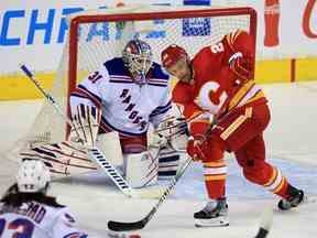 L'attaquant des Flames de Calgary Trevor Lewis cherche à saisir la rondelle devant le gardien de but des Rangers de New York Igor Shesterkin lors d'un match de la LNH le samedi 6 novembre 2021.