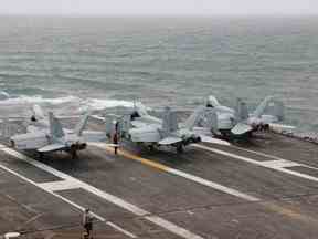 Trois avions de chasse AF/A-18E Super Hornet vus stationnés sur le pont du porte-avions USS Nimitz lors d'un déploiement en mer de Chine méridionale, au milieu de la mer, le 27 janvier 2023.