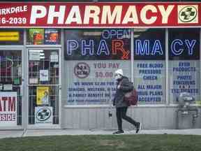 Un piéton passe devant une pharmacie à Parkdale, Toronto.