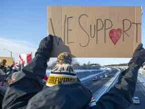 Des partisans applaudissent depuis un viaduc alors que des camions passent dans le cadre du Freedom Convoy en direction d'Ottawa, à Kingston, en Ontario, le 28 janvier 2022.