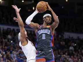 Le garde du Thunder d'Oklahoma City, Shai Gilgeous-Alexander, à droite, cherche à passer le ballon loin de l'attaquant des Cleveland Cavaliers Lamar Stevens lors de la seconde moitié d'un match de basket de la NBA le vendredi 27 janvier 2023 à Oklahoma City.