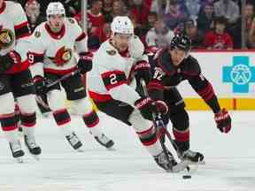 Le défenseur des Sénateurs Artem Zub tente de contrôler la rondelle contre le centre des Hurricanes Jesperi Kotkaniemi lors de la première période du match de vendredi.