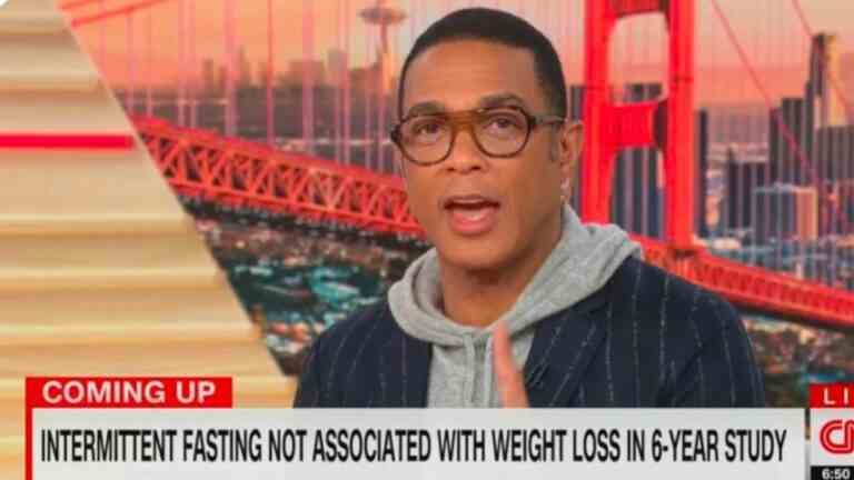 Don Lemon reading the news in a hooded and a suit coat.