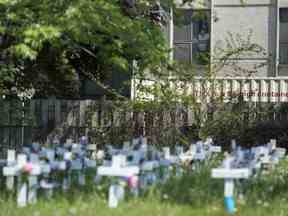 Un homme regarde par la fenêtre du centre communautaire Camilla Care surplombant des croix marquant la mort de plusieurs personnes survenues lors de la pandémie de COVID-19 à Mississauga, en Ontario, le 26 mai 2020.