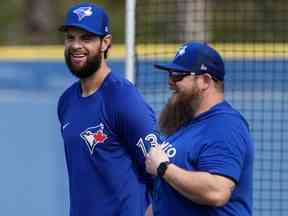 Le frappeur désigné et joueur de premier but des Blue Jays de Toronto Brandon Belt, à gauche, sourit en discutant avec un membre du personnel d'entraînement des Blue Jays lors de l'entraînement printanier de baseball à Dunedin, en Floride, le mardi 21 février 2023.