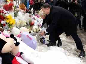 Le premier ministre du Québec François Legault et son épouse Isabelle Brais laissent des fleurs et un ours en peluche alors qu'ils visitent le site de l'accident mortel d'autobus à Laval le jeudi 9 février 2023.