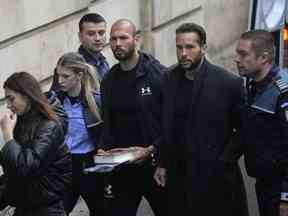 Andrew Tate, troisième à droite, et son frère Tristan, deuxième à droite, sont amenés par des policiers devant la cour d'appel de Bucarest, Roumanie, le mardi 10 janvier 2023. (AP Photo/Vadim Ghirda)