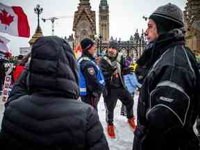 Mathieu Venne de Val-des-Monts, au Québec, s'entretient avec un agent de liaison du Service de police d'Ottawa sur la rue Wellington samedi après-midi.