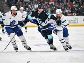 TJ Brodie des Maple Leafs (à gauche) et Matty Beniers de Kraken et Auston Matthews des Maple Leafs (à droite) poursuivent la rondelle au cours de la deuxième période au Climate Pledge Arena le dimanche 26 février 2023.