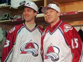 Les joueurs nouvellement acquis de l'Avalanche du Colorado Patrick Roy, à gauche, et Mike Keane sourient en enfilant le maillot de leur nouvelle équipe lors d'une conférence de presse dans le vestiaire du McNichols Sports Arena de Denver le 6 décembre 1995. Les deux ont été échangés à l'Avalanche dans le cadre d'une entente à cinq joueurs avec les Canadiens de Montréal.