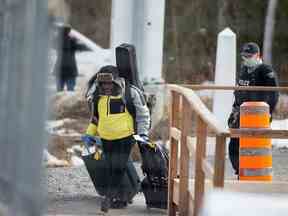 Un demandeur d'asile traverse la frontière de New York au Canada, suivi d'un agent de la Gendarmerie royale du Canada (GRC) à Roxham Road à Hemmingford, Québec, Canada le 18 mars 2020. REUTERS/Christinne Muschi