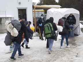 Une famille de demandeurs d'asile colombiens est accueillie par des agents de la GRC après avoir traversé la frontière à Roxham Road vers le Canada le jeudi 9 février 2023 à Champlain, New York.