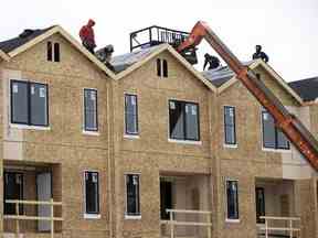 Équipes travaillant à la pose de bardeaux dans un complexe d'habitation à logements multiples à Regina, en Saskatchewan.