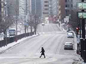 Une femme portant un masque facial traverse le boulevard René-Lévesque à Montréal alors que la pandémie de COVID-19 se poursuit au Canada et dans le monde en 2021.