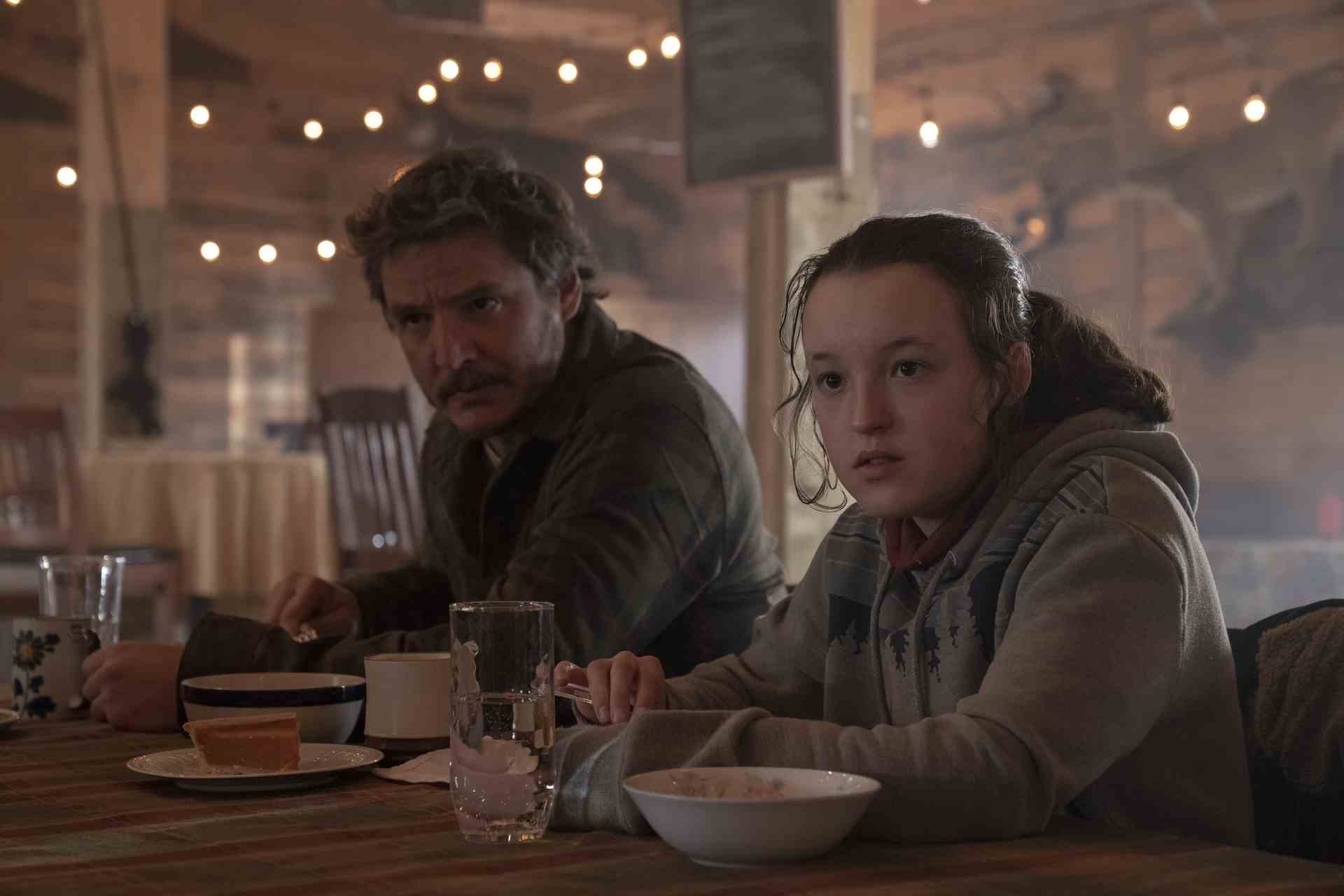 Joel (Pedro Pascal) and Ellie (Bella Ramsey) eat a hot meal in the mess hall of Jackson, Wyoming