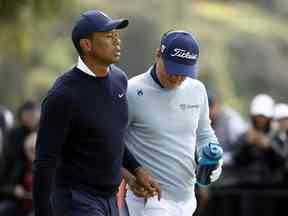 Tiger Woods remet à Justin Thomas un article considéré comme un tampon alors qu'ils sortent du neuvième tee lors du premier tour du Genesis Invitational au Riviera Country Club le 16 février 2023 à Pacific Palisades, en Californie.