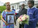 Marie-Mireille Bence avec une photo de son fils Jean-René Olivier devant sa maison de Repentigny lundi.  Le fils d'Olivier, Kayshawn, tient des fleurs.