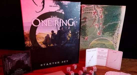 The One Ring Starter Set box, map, cards, and dice on a wooden table against a dark backdrop