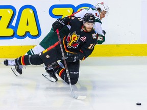 Le centre des Flames de Calgary Jonathan Huberdeau (10) et le centre du Wild du Minnesota Joel Eriksson Ek (14) se battent pour la rondelle lors de la première période au Scotiabank Saddledome le samedi 4 mars 2023.