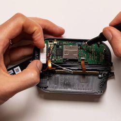 Cette image montre l'intérieur d'un Joy-Con droit, qui a une disposition légèrement différente.  Cependant, les étapes pour atteindre et installer un joystick sont similaires.