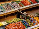 Une personne pousse un caddie dans la section des produits d'une épicerie à Toronto.