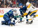 Le gardien de but des Canucks de Vancouver Arturs Silovs fait un arrêt de gant avant que Yakov Trenin des Nashville Predators ne puisse mettre son bâton sur la rondelle pendant la deuxième période à Vancouver le lundi 6 mars 2023. Kyle Burroughs des Canucks tente d'aider à défendre sur le jeu.