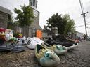 De nombreuses chaussures pour enfants reposent sur le trottoir menant à l'église catholique de la mission St. Francis Xavier à Kahnawake, le dimanche 30 mai 2021. Elles ont été apportées par les résidents pour honorer les 215 enfants dont les tombes anonymes ont été retrouvées dans un pensionnat en Colombie-Britannique.