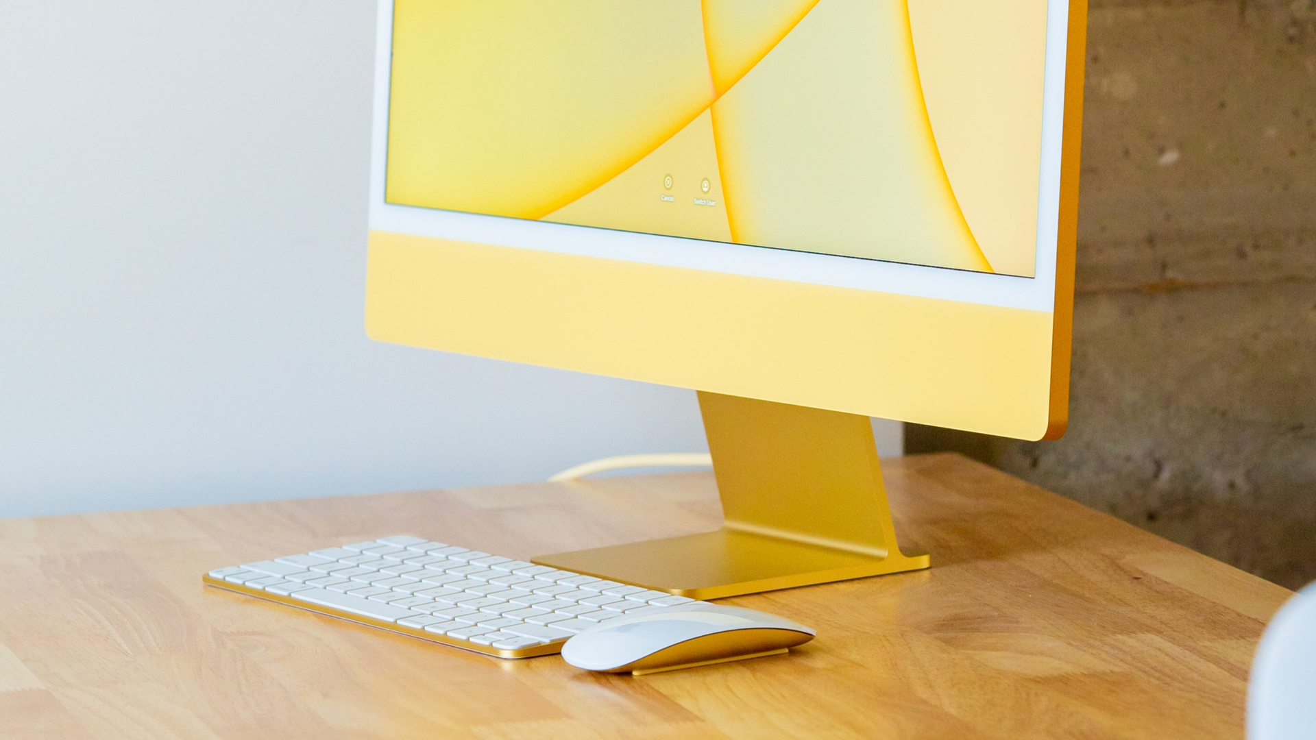 Un iMac jaune sur un bureau en bois avec des périphériques Bluetooth à côté