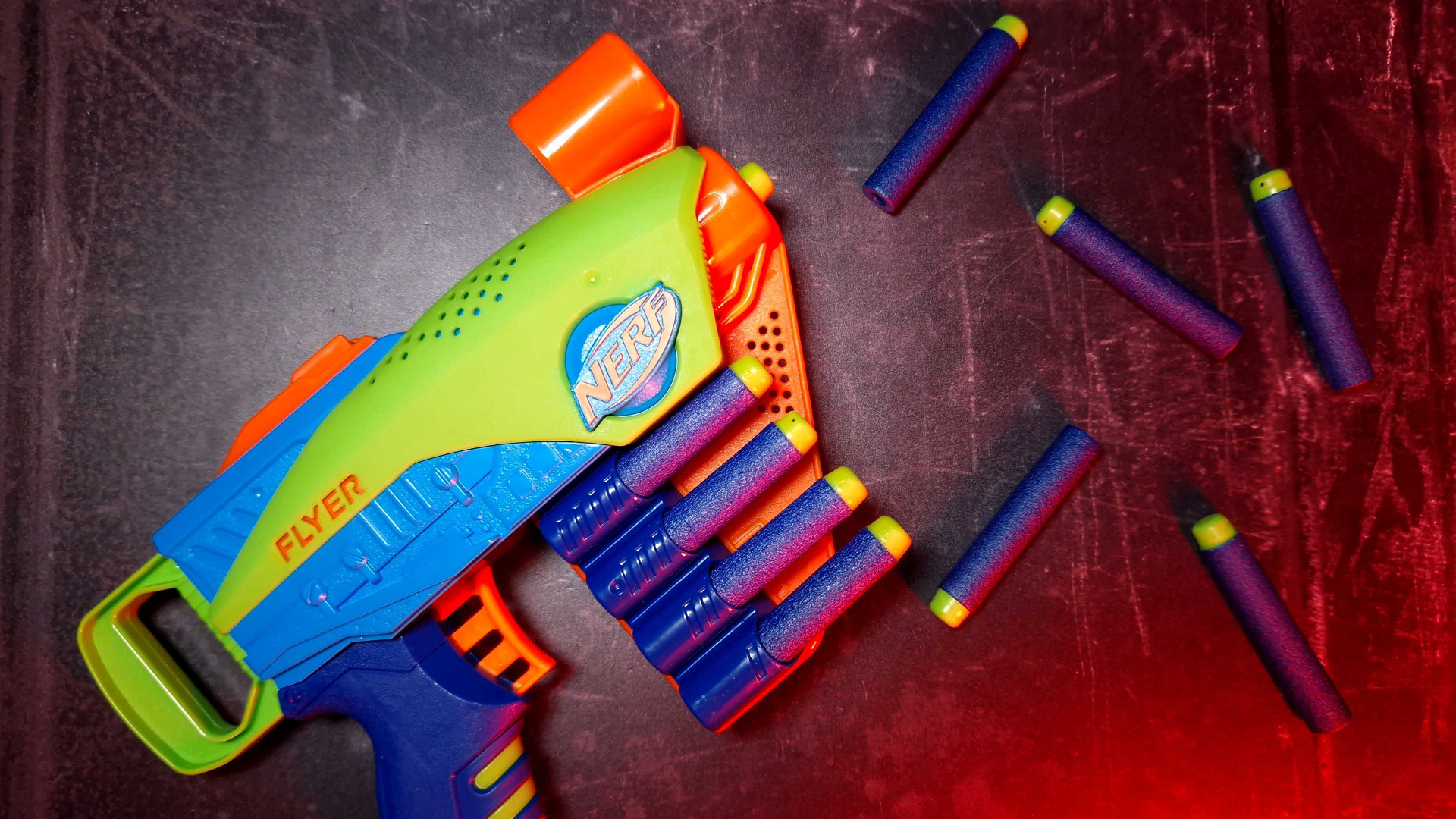 Un Nerf Elite Jr. Flyer assis à côté des fléchettes Nerf Elite