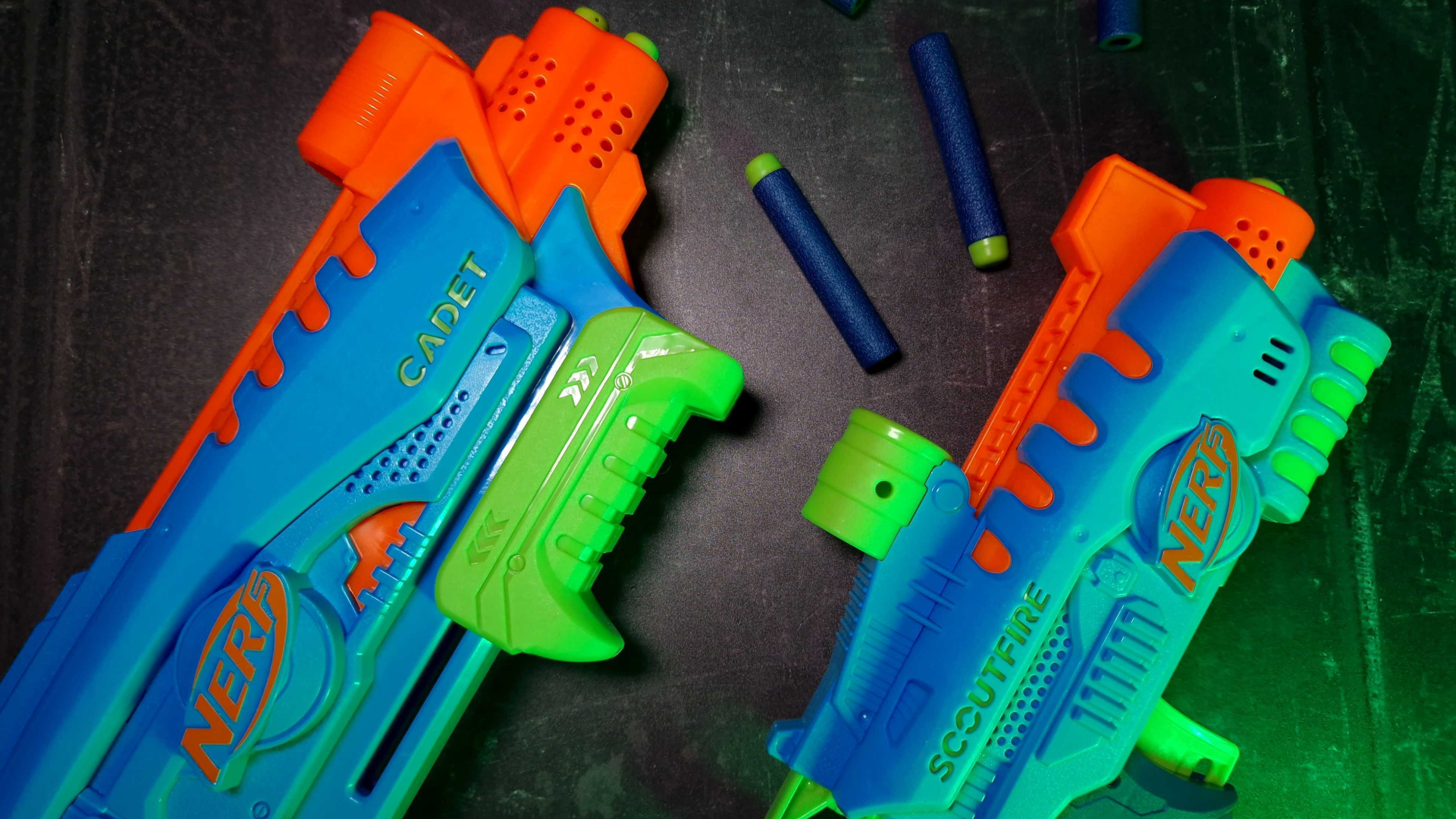 Nerf Elite Jr. Starter Set blasters disposés les uns à côté des autres, avec des fléchettes, sur un fond sombre