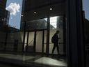 Un homme marche dans un immeuble de bureaux du centre-ville de Toronto avec d'autres bâtiments reflétés dans une fenêtre sur cette photo du 11 juin 2019.