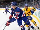 Le défenseur Tyler Kleven tente de repousser la pression d'échec avant de Fabian Lysell, à droite, lors d'un match de championnat du monde de hockey junior entre les États-Unis et la Suède à Edmonton en août.