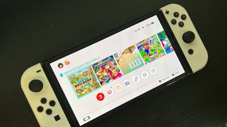 Nintendo Switch console on black table, on to show homescreen with games and battery level indicator