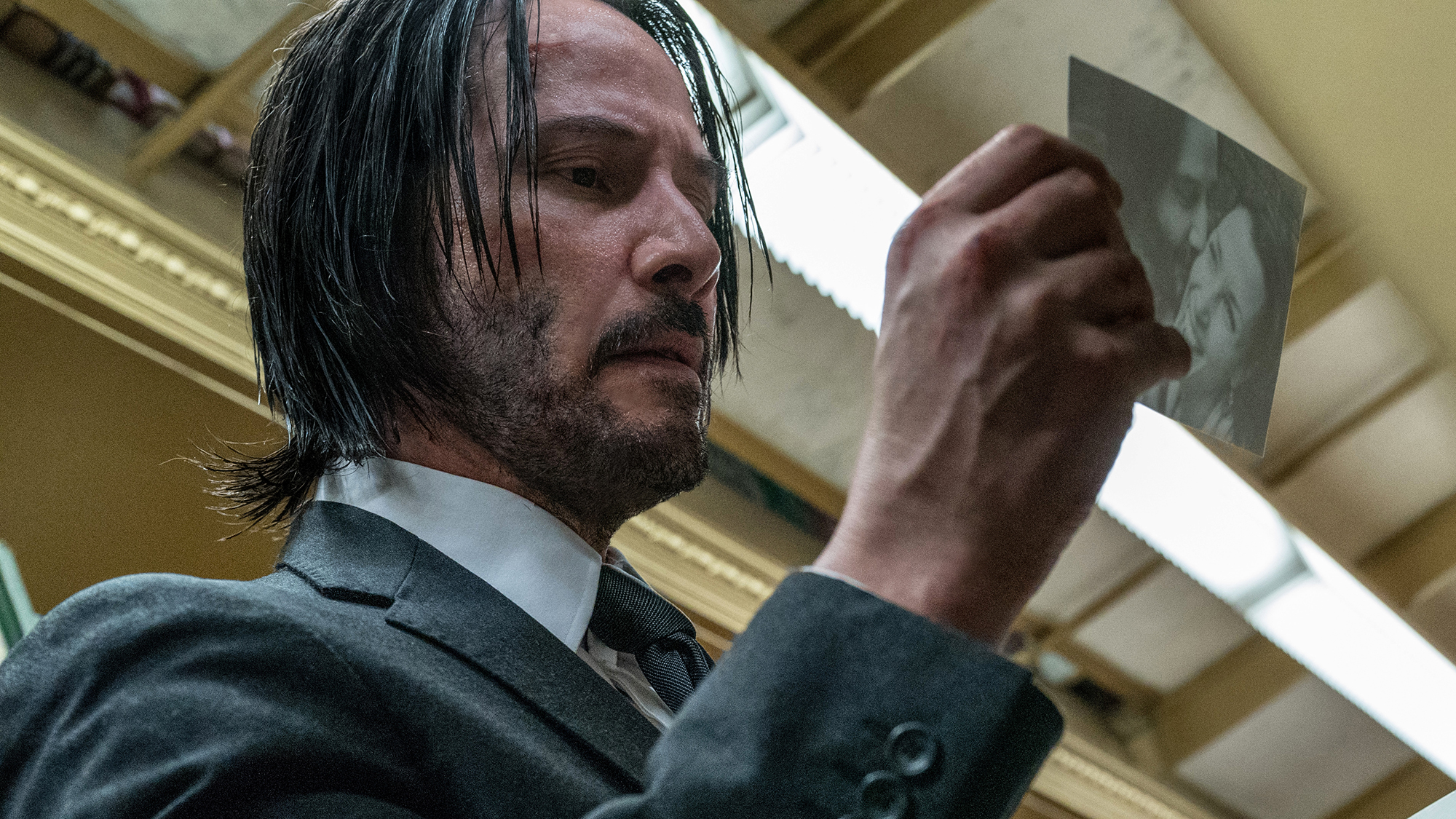 Keanu Reeves dans le rôle de John Wick, regardant une photo dans John Wick: Chapitre 3 - Parabellum